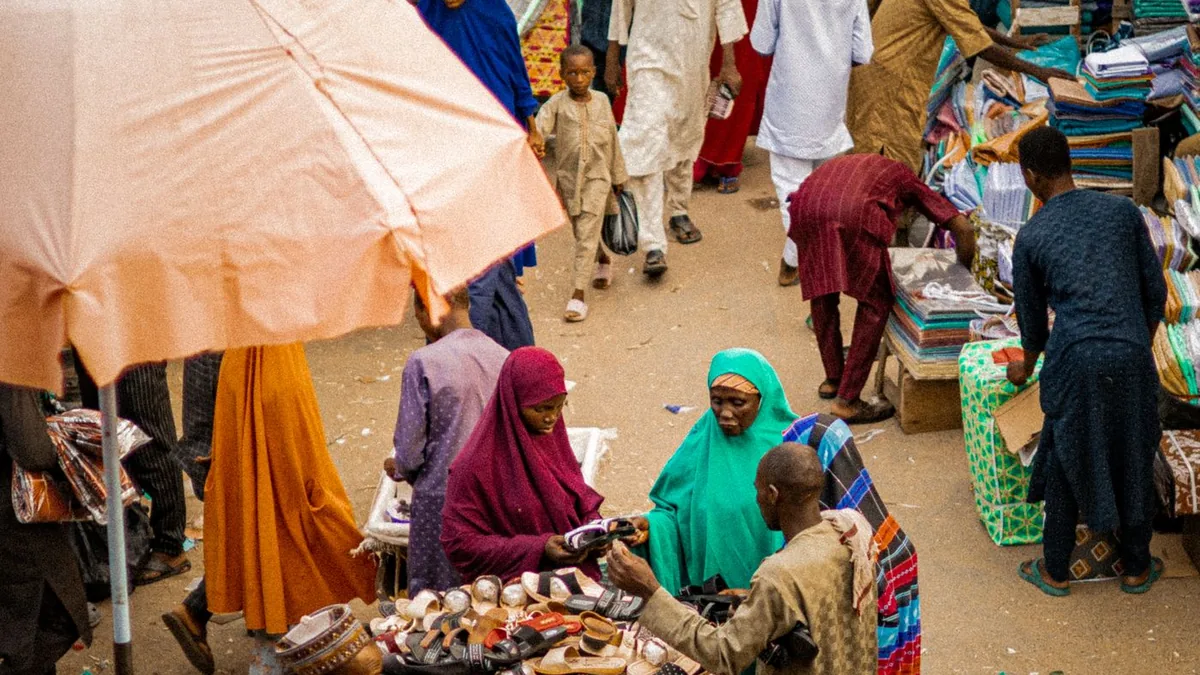 Un marché africain animé vu de haut, étals et parasols colorés au milieu de la foule