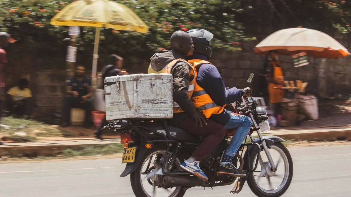 Un coursier à moto transporte un colis dans une rue animée de Nairobi