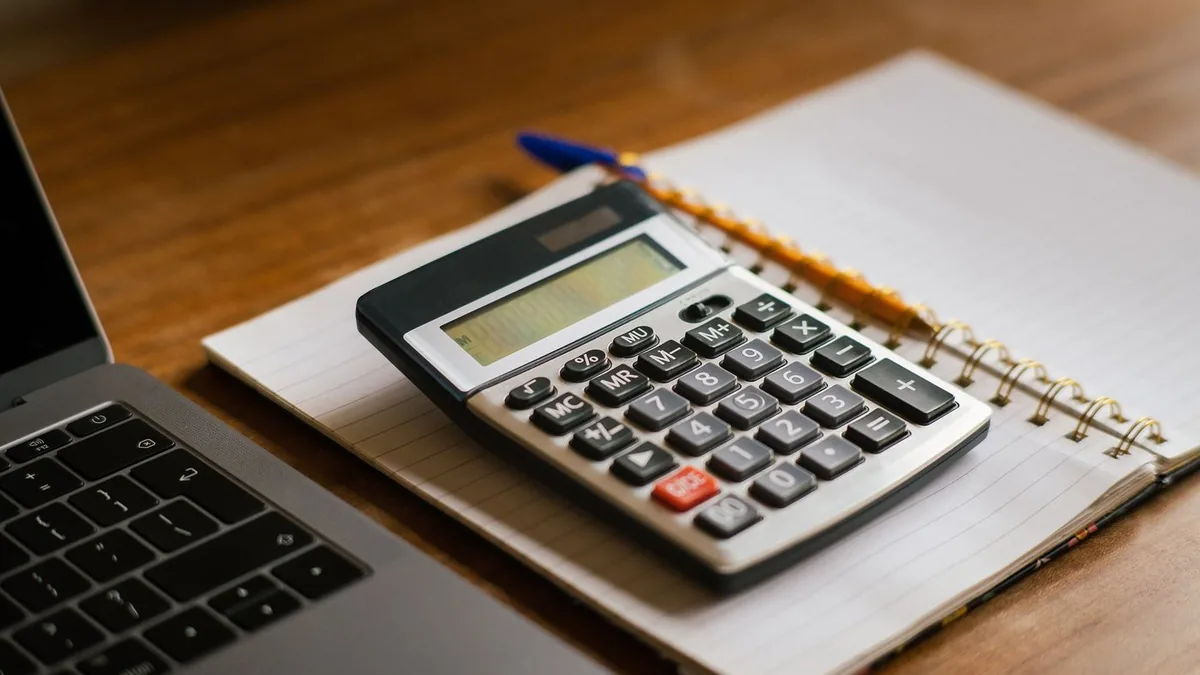 Une calculatrice posée sur un carnet ouvert, à côté d’un ordinateur portable