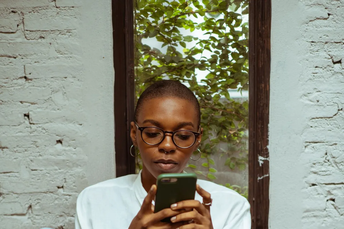 Une jeune femme assise, concentrée sur son téléphone